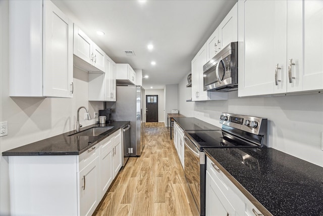 kitchen featuring light wood-type flooring, appliances with stainless steel finishes, white cabinetry, and sink