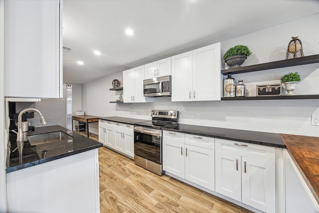 kitchen featuring white cabinets, appliances with stainless steel finishes, wooden counters, light hardwood / wood-style floors, and sink