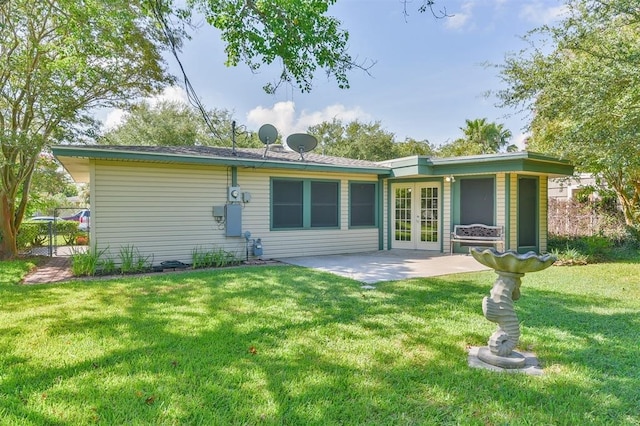 back of property with a patio area, french doors, and a yard