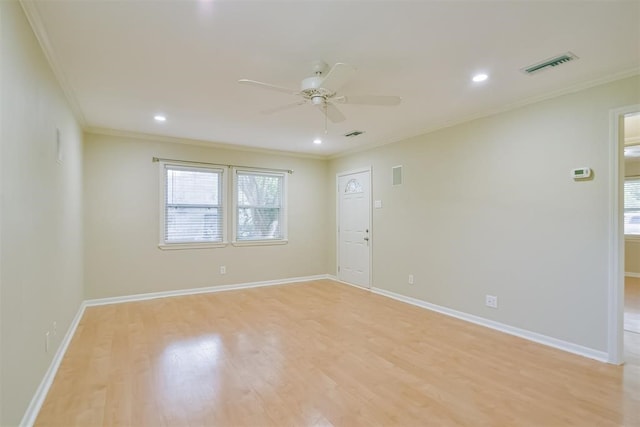 empty room with a wealth of natural light, crown molding, and light hardwood / wood-style flooring