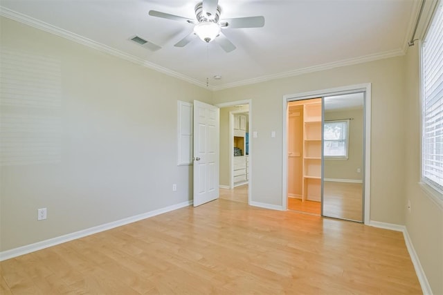 unfurnished bedroom featuring ceiling fan, light wood-type flooring, a closet, ornamental molding, and multiple windows