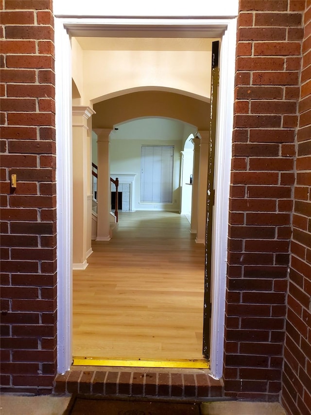 hallway featuring hardwood / wood-style floors and ornate columns