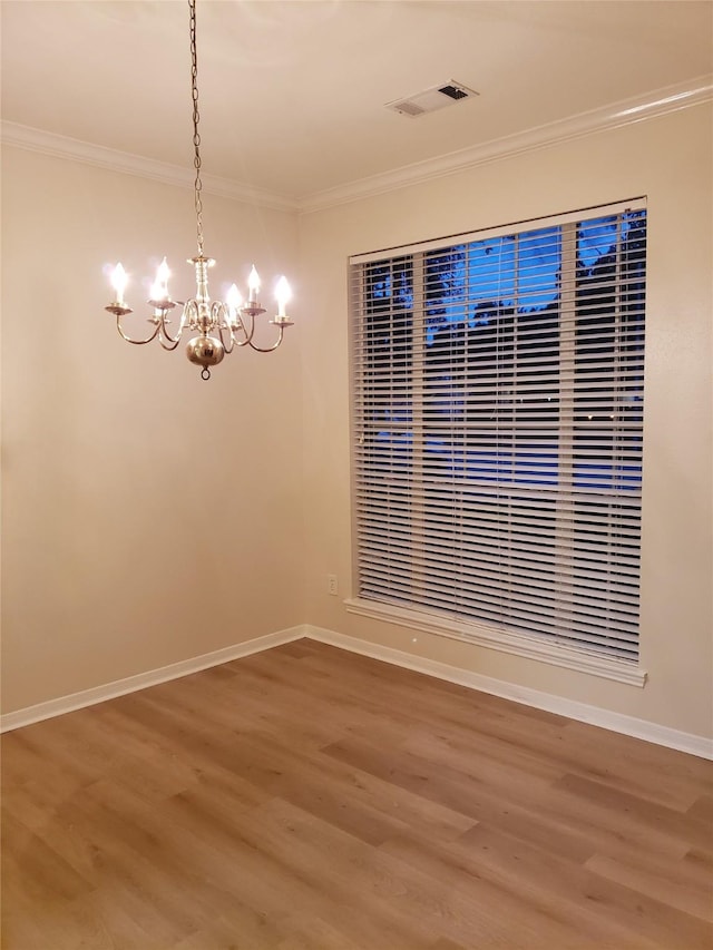 unfurnished dining area featuring hardwood / wood-style flooring, ornamental molding, and a chandelier