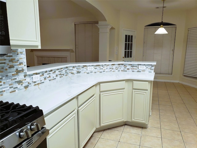 kitchen featuring decorative light fixtures, ornate columns, decorative backsplash, kitchen peninsula, and light tile patterned floors