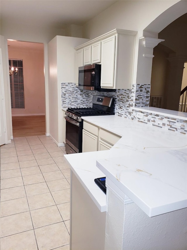 kitchen with kitchen peninsula, decorative backsplash, white cabinetry, appliances with stainless steel finishes, and light tile patterned floors