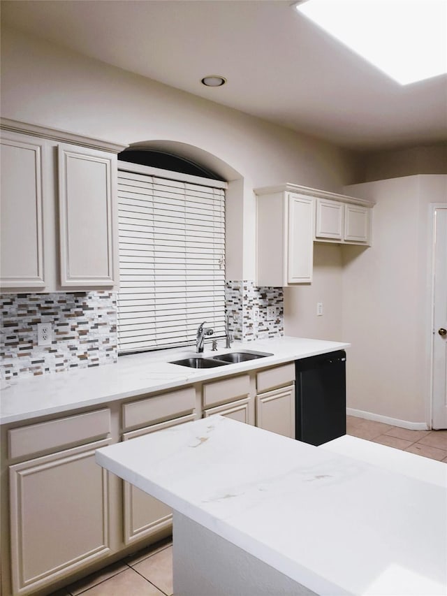 kitchen featuring decorative backsplash, sink, black dishwasher, light stone countertops, and light tile patterned floors