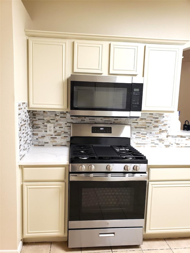 kitchen with tasteful backsplash, light tile patterned floors, stainless steel appliances, and cream cabinets