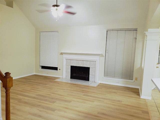 unfurnished living room with vaulted ceiling, ceiling fan, a fireplace, and light hardwood / wood-style flooring