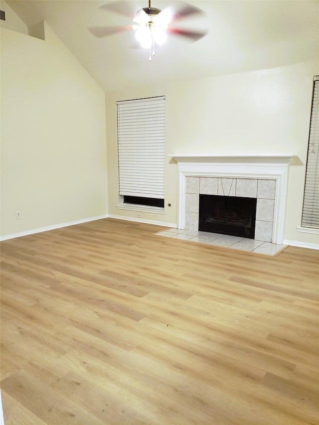 unfurnished living room with ceiling fan, light hardwood / wood-style floors, a tile fireplace, and vaulted ceiling