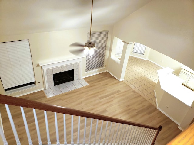 unfurnished living room featuring ceiling fan, tile patterned floors, and a tile fireplace