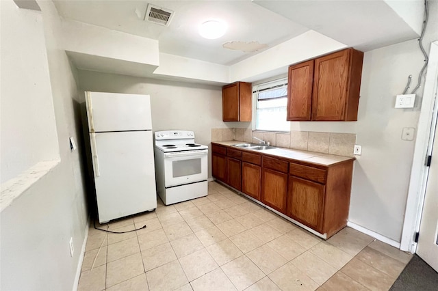 kitchen with light tile patterned floors, tile counters, sink, and white appliances