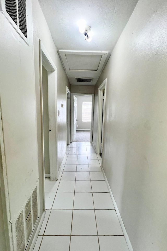 corridor featuring light tile patterned floors and a textured ceiling