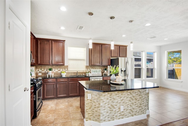 kitchen featuring dark stone countertops, pendant lighting, a center island, appliances with stainless steel finishes, and light tile patterned floors