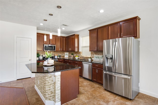 kitchen with appliances with stainless steel finishes, a kitchen island, decorative light fixtures, dark stone countertops, and decorative backsplash