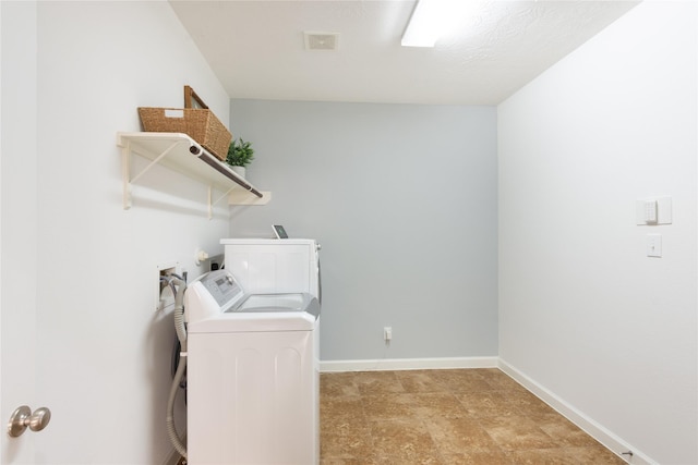 laundry area with washer and clothes dryer and a textured ceiling