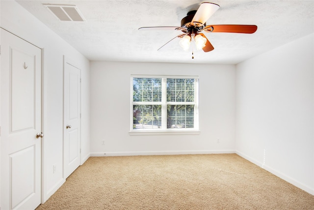 unfurnished bedroom with light carpet, ceiling fan, and a textured ceiling