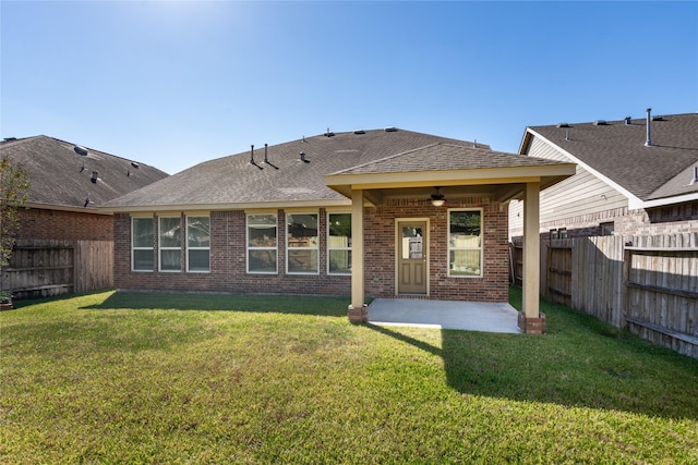 rear view of property featuring ceiling fan, a patio area, and a yard