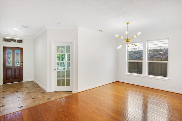 foyer featuring a wealth of natural light, wood-type flooring, crown molding, and a chandelier