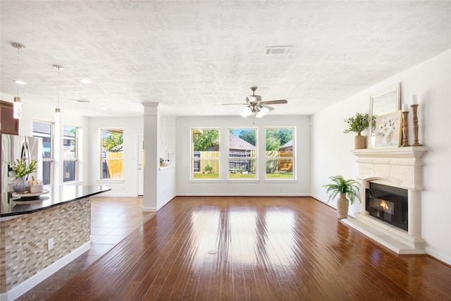 unfurnished living room with ceiling fan, dark hardwood / wood-style flooring, and ornate columns