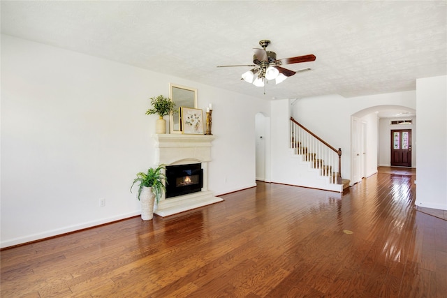 unfurnished living room featuring a textured ceiling, ceiling fan, and dark hardwood / wood-style flooring