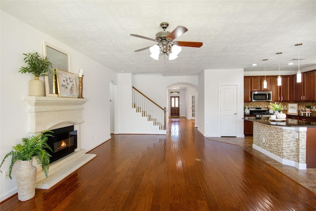 living room with ceiling fan, dark hardwood / wood-style flooring, and a textured ceiling