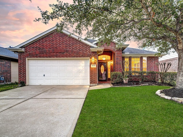 ranch-style house with a garage, concrete driveway, brick siding, and a lawn