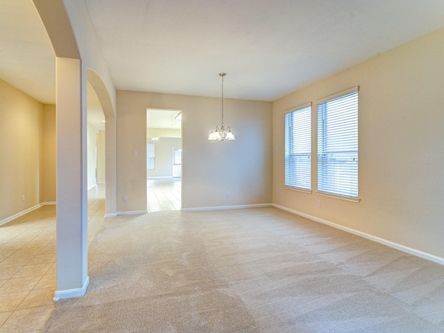 spare room featuring an inviting chandelier and light colored carpet