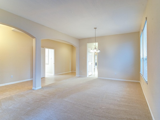 carpeted spare room with an inviting chandelier