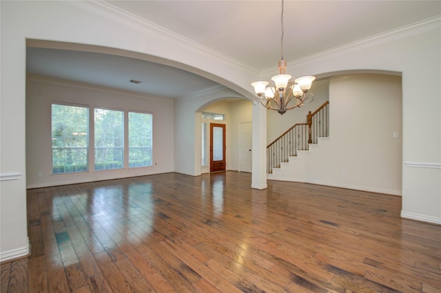 spare room featuring dark hardwood / wood-style flooring, an inviting chandelier, and ornamental molding