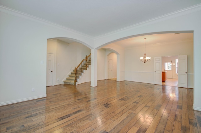 empty room featuring hardwood / wood-style floors, crown molding, and an inviting chandelier