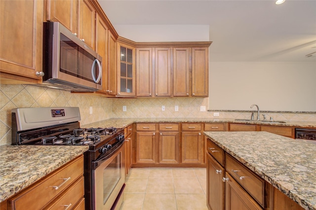 kitchen featuring appliances with stainless steel finishes, sink, backsplash, light stone counters, and light tile patterned floors