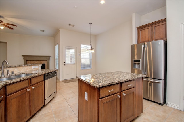 kitchen featuring light tile patterned floors, appliances with stainless steel finishes, a center island, hanging light fixtures, and sink