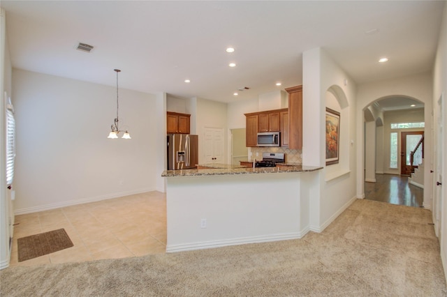 kitchen with decorative light fixtures, backsplash, kitchen peninsula, light stone countertops, and stainless steel appliances