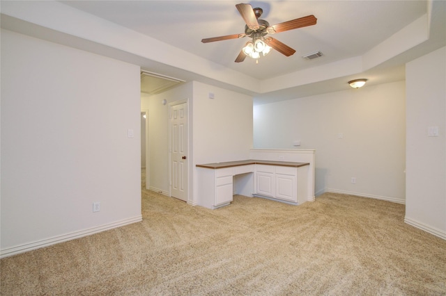 carpeted spare room with ceiling fan and a raised ceiling