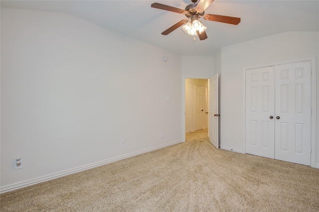 unfurnished bedroom featuring lofted ceiling, ceiling fan, a closet, and light colored carpet