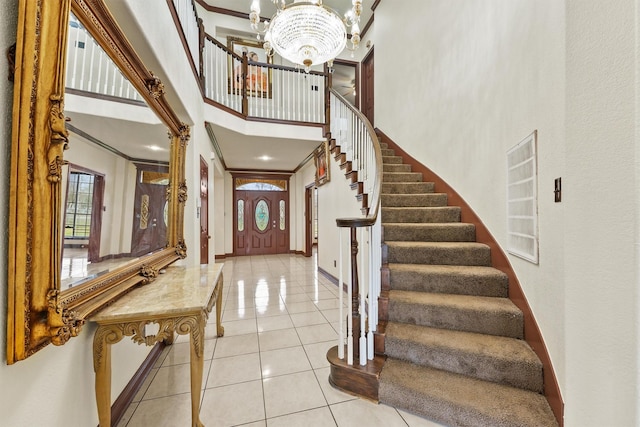 entrance foyer with a chandelier, light tile patterned flooring, a high ceiling, and ornamental molding