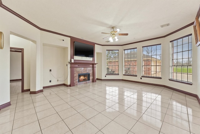 unfurnished living room with ceiling fan, light tile patterned flooring, crown molding, and a fireplace