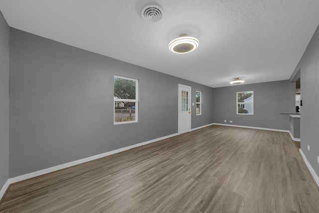 unfurnished living room featuring a textured ceiling and wood-type flooring