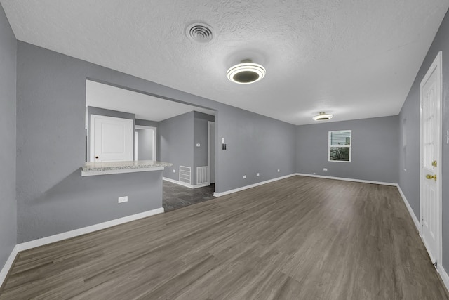 unfurnished room featuring dark wood-type flooring and a textured ceiling