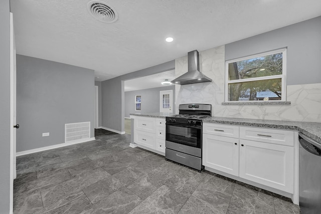 kitchen with wall chimney exhaust hood, gas range oven, dishwasher, and white cabinets