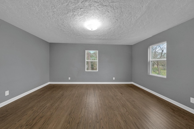 empty room with dark hardwood / wood-style flooring and a textured ceiling