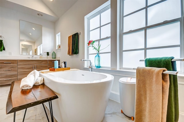 bathroom featuring a bath, vaulted ceiling, and vanity