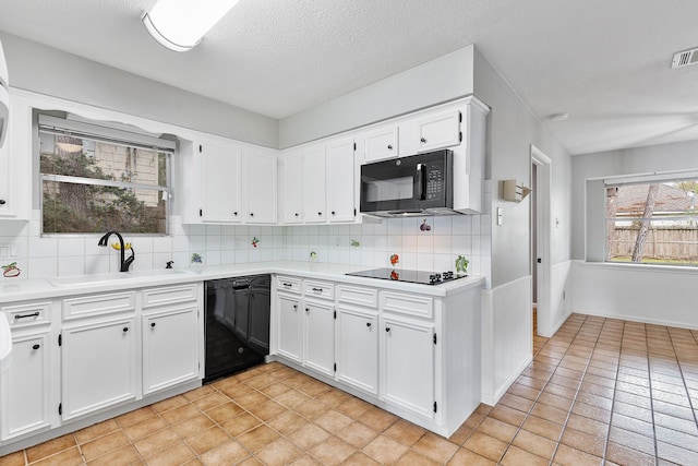 kitchen with backsplash, black appliances, sink, white cabinetry, and light tile patterned floors