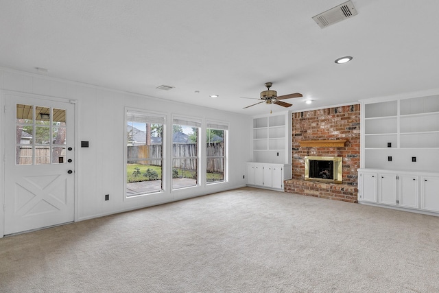 unfurnished living room with ceiling fan, a fireplace, ornamental molding, light carpet, and built in shelves