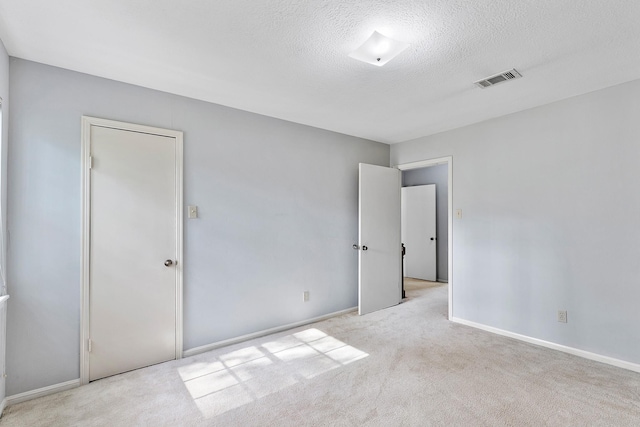 unfurnished bedroom featuring light colored carpet, a closet, and a textured ceiling