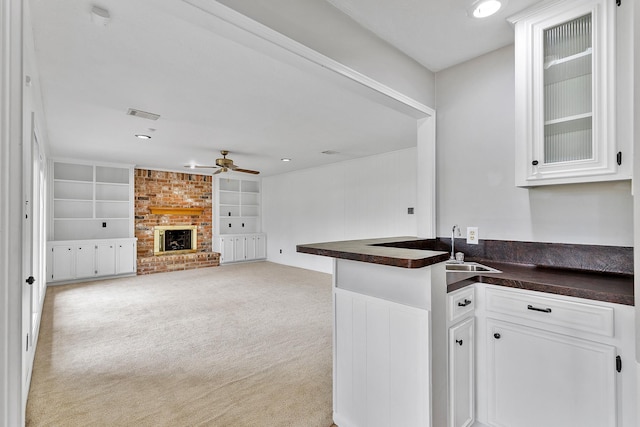 kitchen with light colored carpet, white cabinets, built in features, and kitchen peninsula