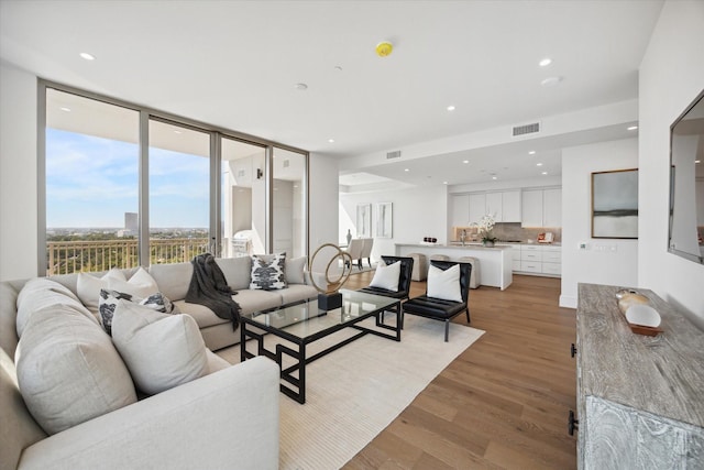 living room with light wood-style floors, visible vents, and recessed lighting