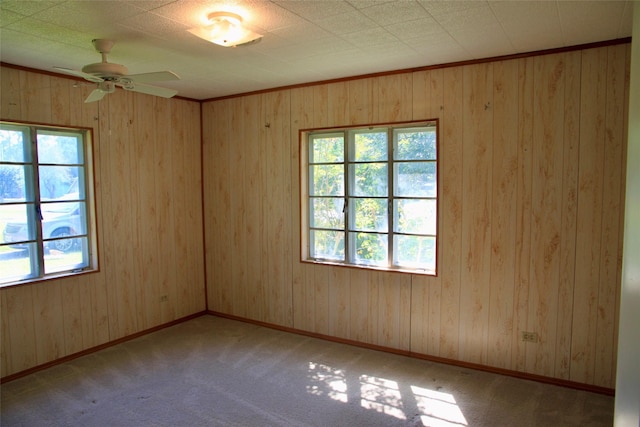 spare room featuring ceiling fan, light colored carpet, a wealth of natural light, and ornamental molding