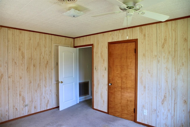 unfurnished bedroom with ceiling fan, crown molding, and carpet floors