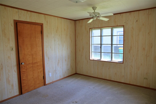 empty room featuring ceiling fan, crown molding, and light colored carpet